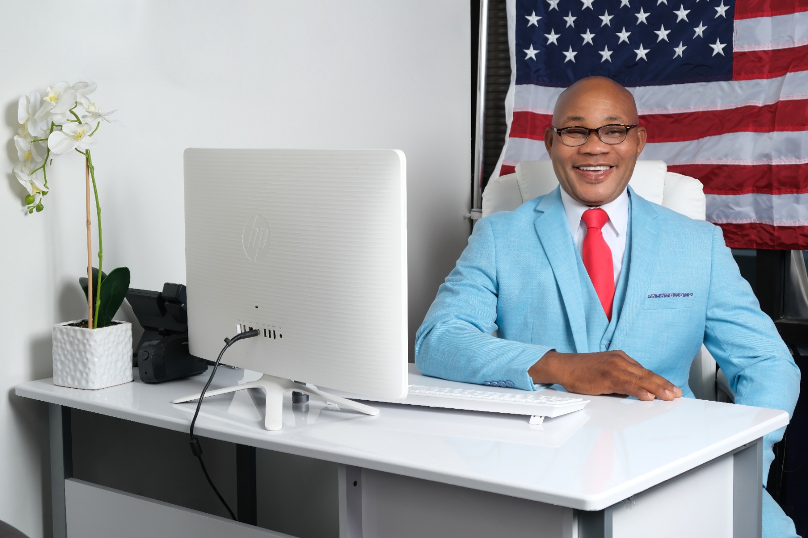 Caneste Succe working at his desk beside the American flag
